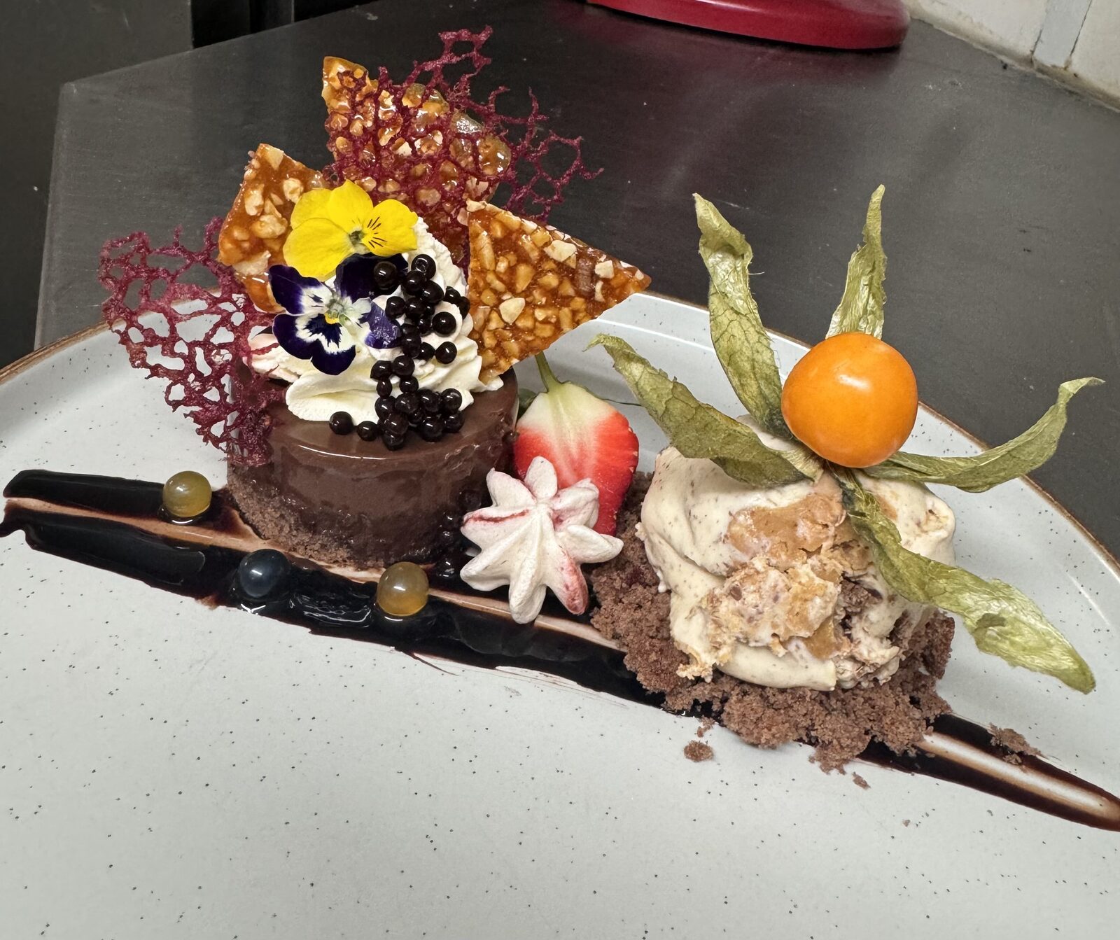 Chocolate delice plated with berries and a chocolate shard.