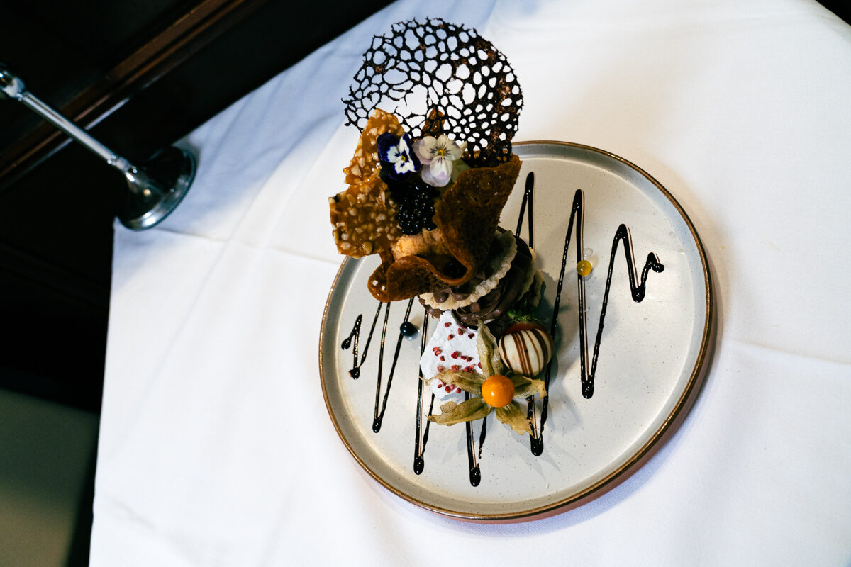 A plated dessert with a spun sugar decoration and edible flowers.