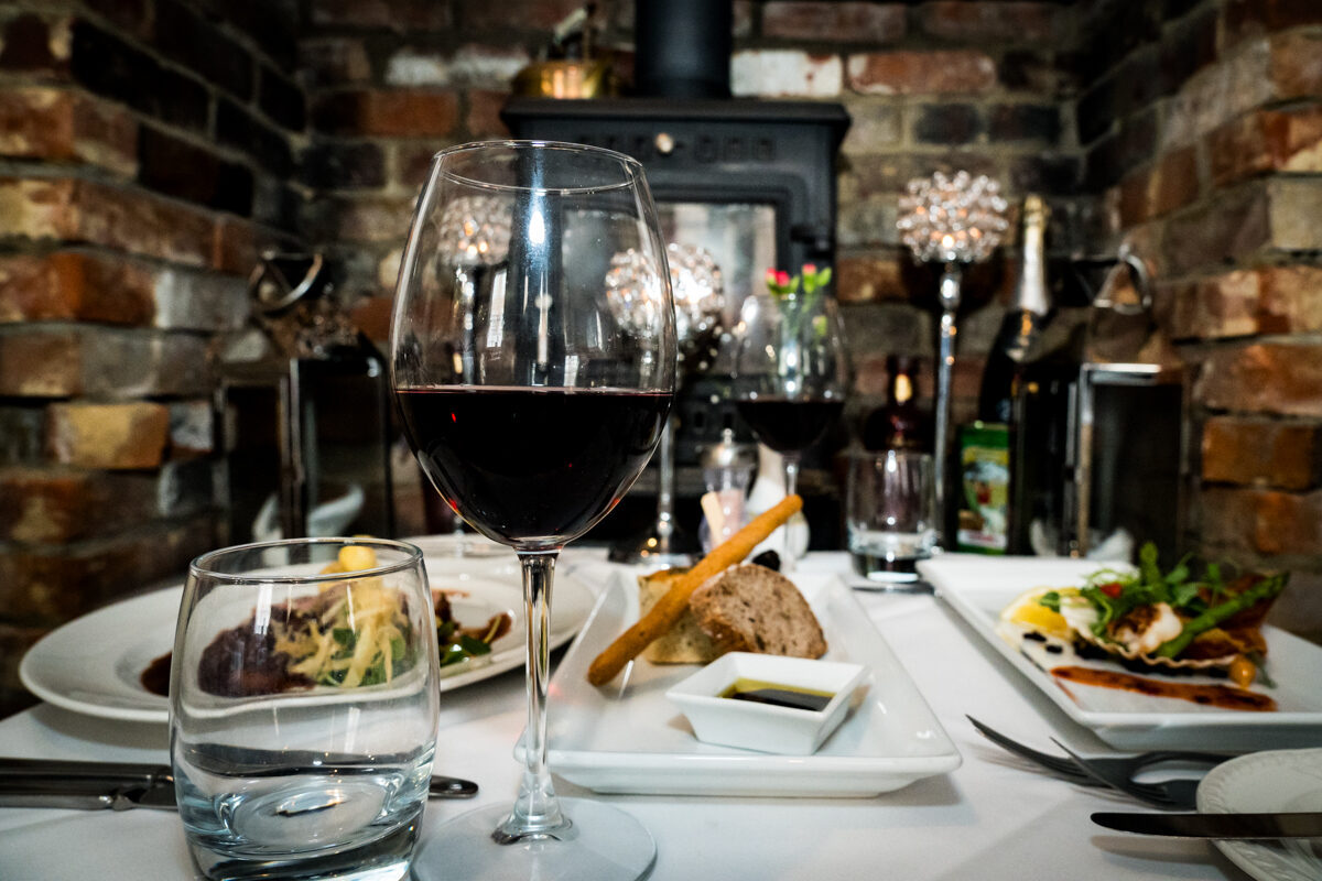 A candlelit table for two beside the brick fireplace.
