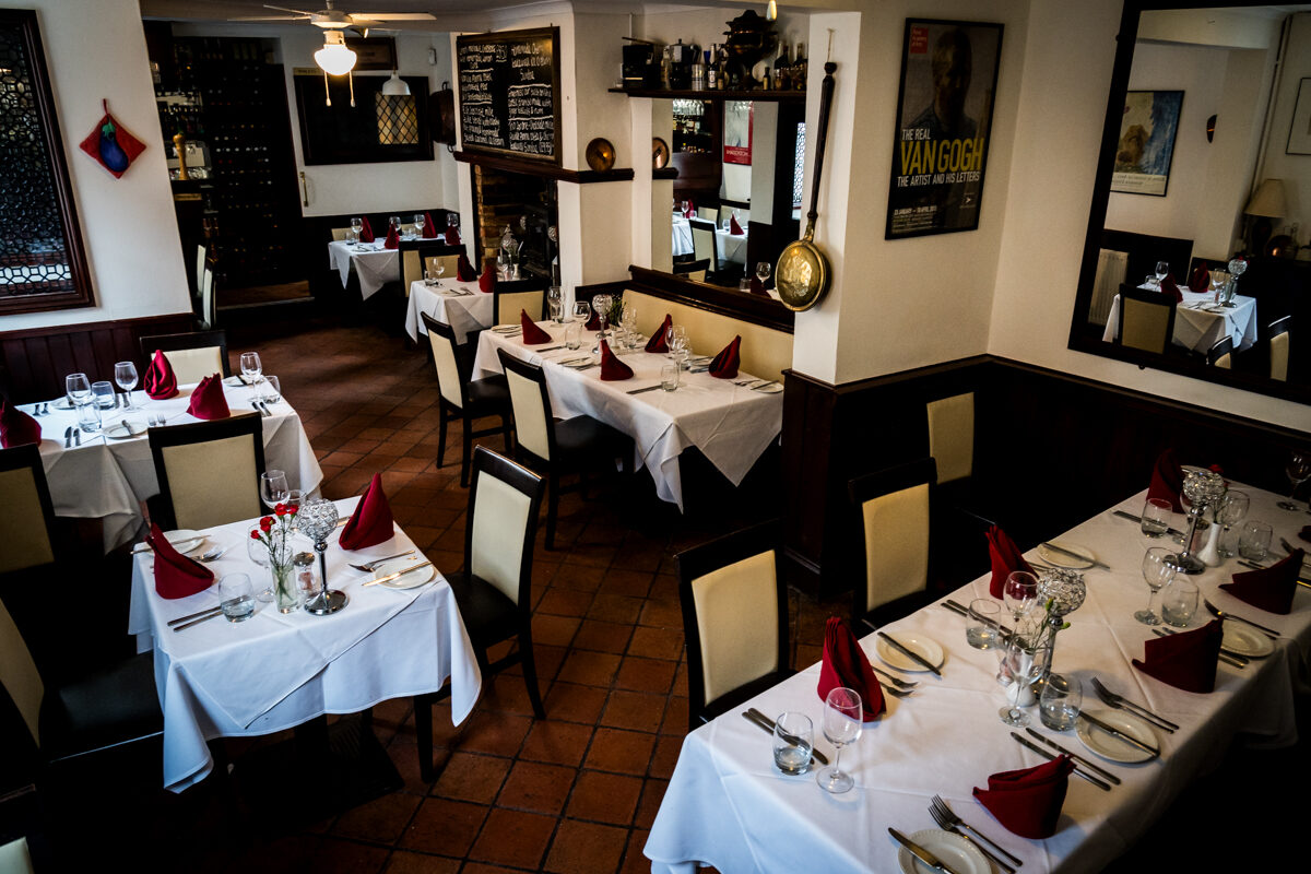 The Burrs dining room, tables laid with white linen and red napkins.